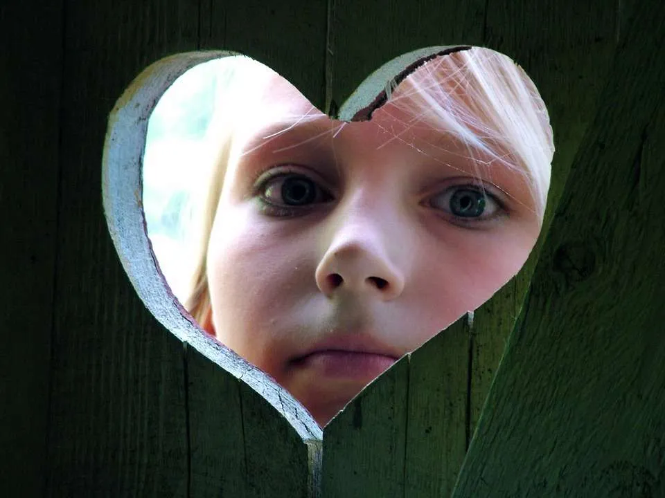 Kind zindelijk maken. Kind kijkt door hartje van wc deur