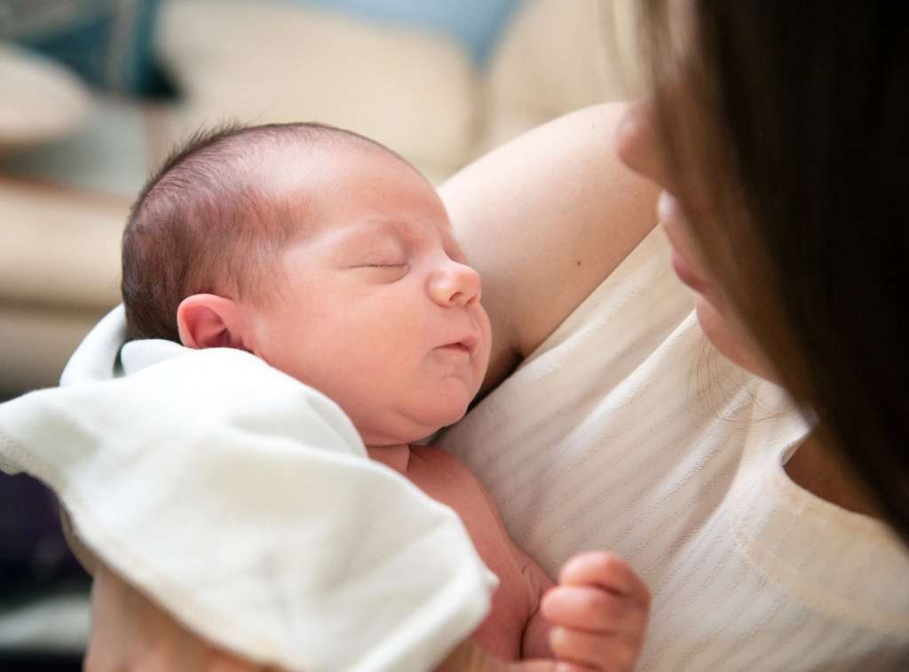 De hik bij baby's Moeder kijkt bezorgd naar haar baby.
