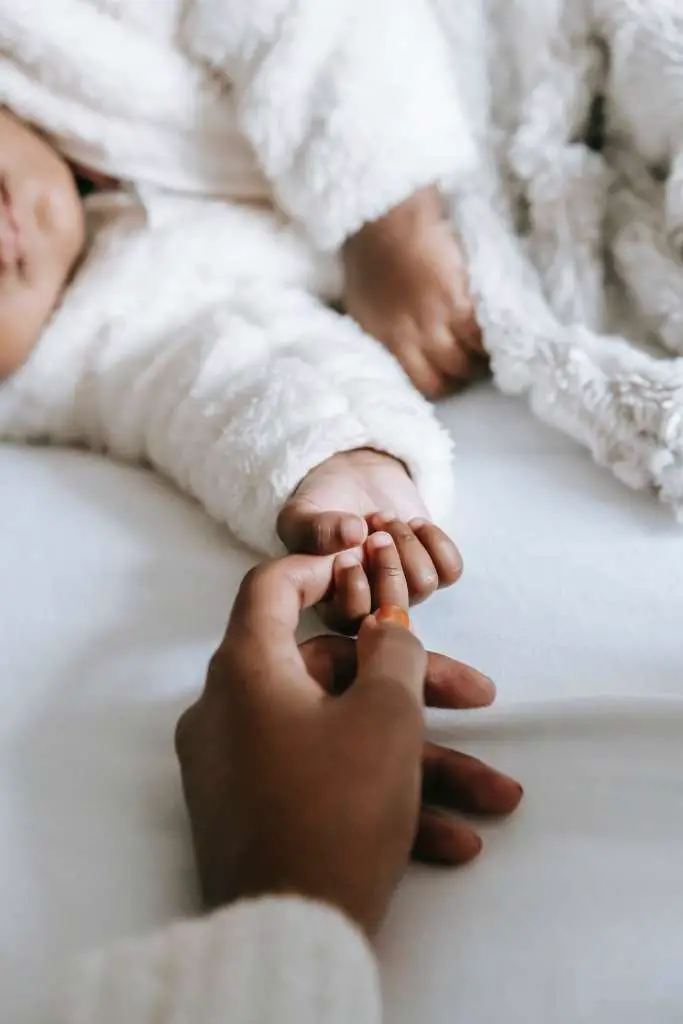Slaapproblemen bij kinderen. Baby houdt vinger van moeder vast.
